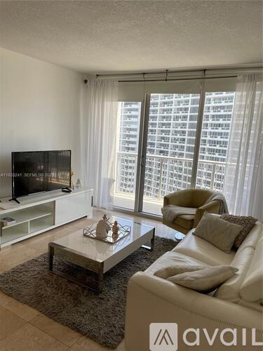 A living room with a white couch, a coffee table, and a flat screen TV.