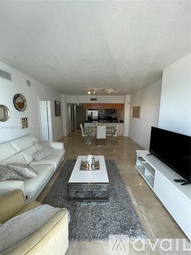 A living room with a white couch and a grey rug.