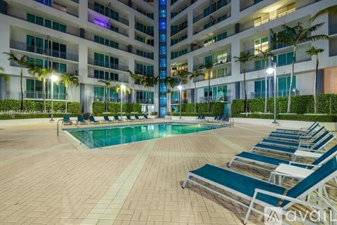 A pool area with lounge chairs and a building in the background.