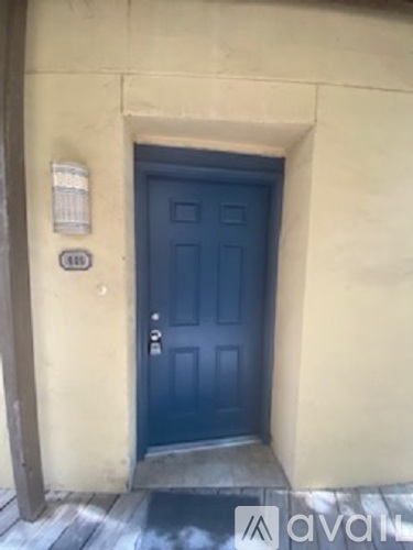 A dark blue door is set in a beige wall.