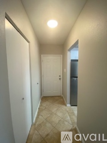 A hallway with a tiled floor and a door on the right.