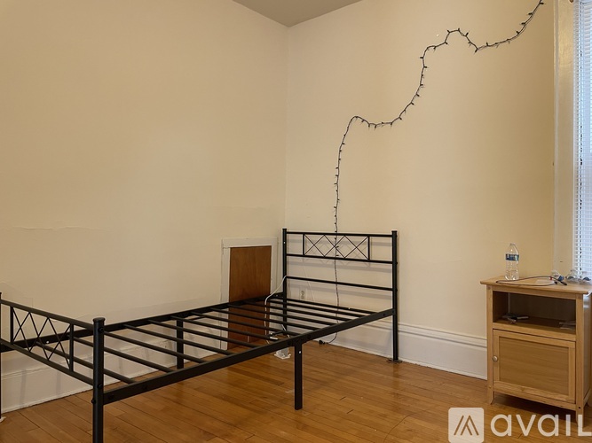 A bedroom with a black metal bed frame and wooden flooring.