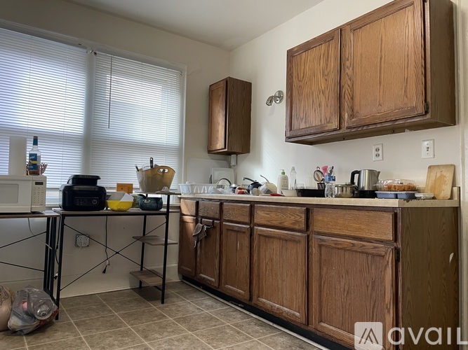 A kitchen with wooden cabinets and a table with various items on it.
