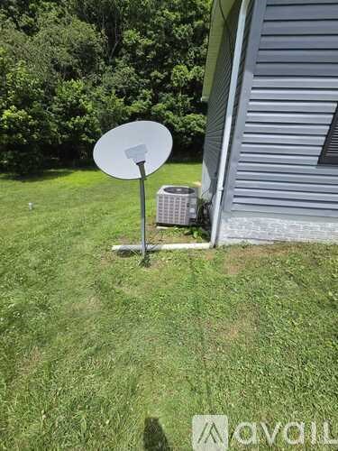A satellite dish is mounted on a pole in a grassy area.
