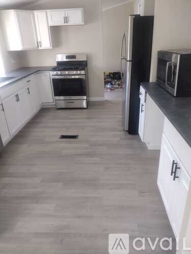 A kitchen with white cabinets and a black fridge.
