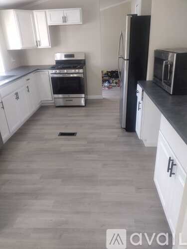 A kitchen with white cabinets and a black fridge.