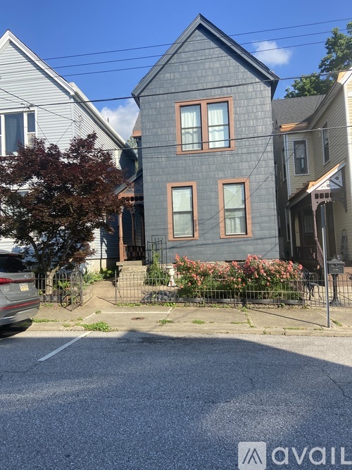 A grey house with a tree in front of it.