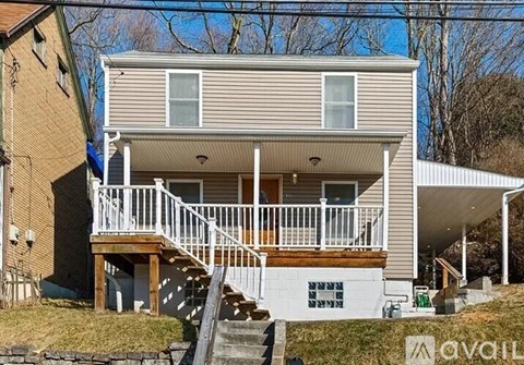 A two-story house with a deck and stairs leading to the entrance.
