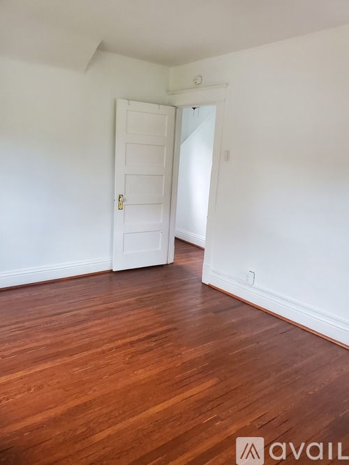 A room with a white door and wooden flooring.