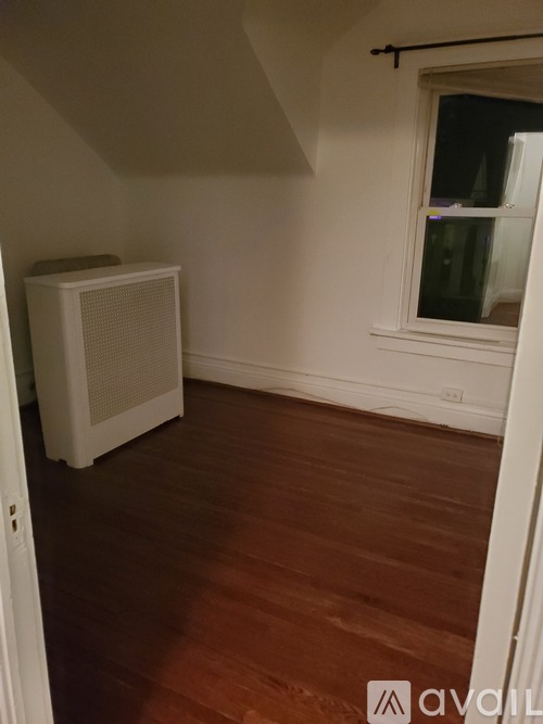 A room with a window and a white radiator on the floor.