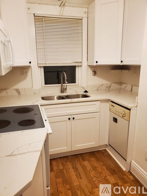 A kitchen with white cabinets and a wooden floor.