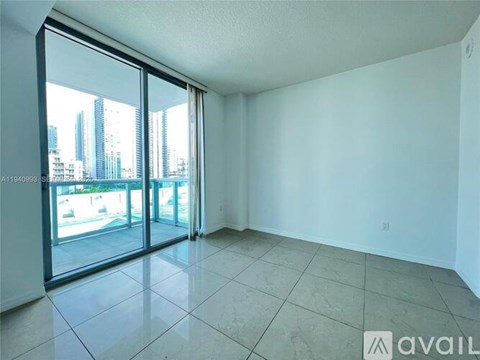A spacious room with tiled flooring and sliding glass doors leading to a balcony.