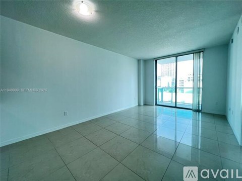 Empty room with tiled floor and sliding glass door.