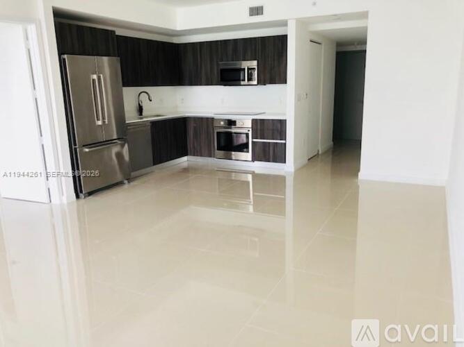 A kitchen with a refrigerator, oven, and sink.