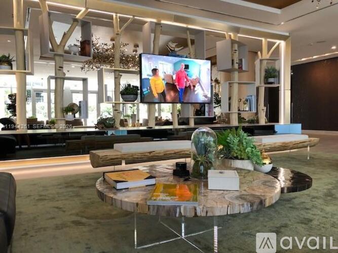 A modern living room with a large TV screen and a coffee table with a plant on it.