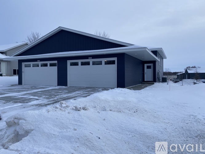 A two-car garage with a blue exterior is surrounded by snow.