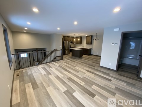 A spacious living room with a kitchen in the background.
