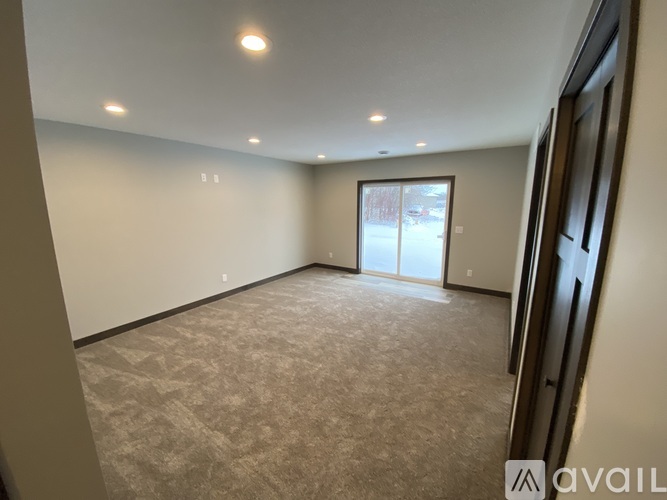 A spacious room with a carpeted floor and a sliding glass door leading to a balcony.
