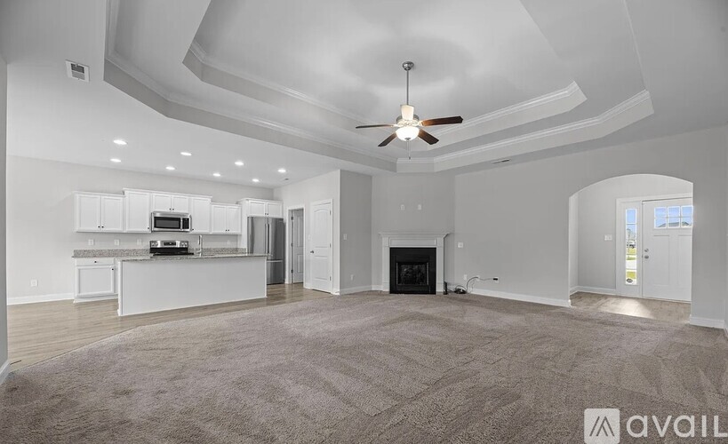 A spacious living room with a fireplace and a ceiling fan.