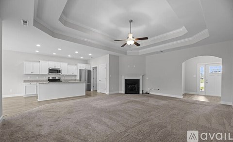 A spacious living room with a fireplace and a ceiling fan.