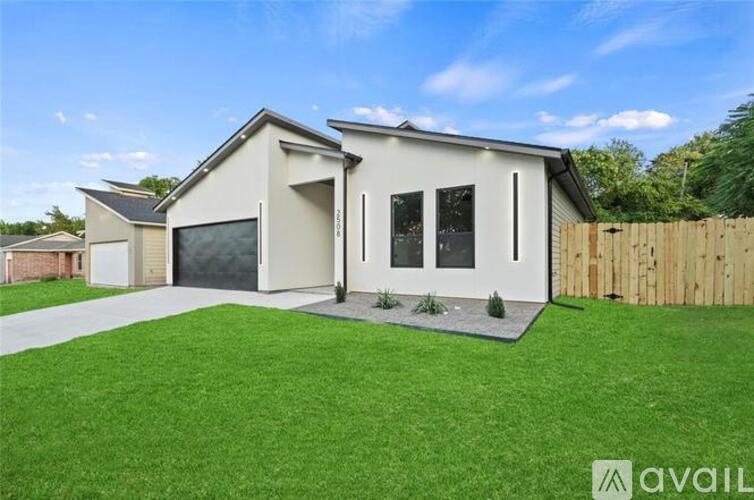 A modern house with a large front yard and a wooden fence.
