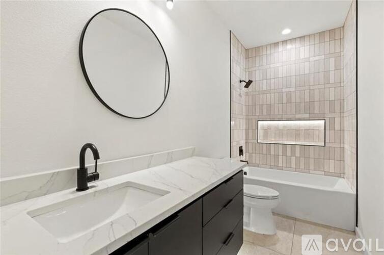 A bathroom with a marble sink and a round mirror.