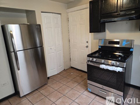 A kitchen with a stainless steel refrigerator, a stove, and a white door.