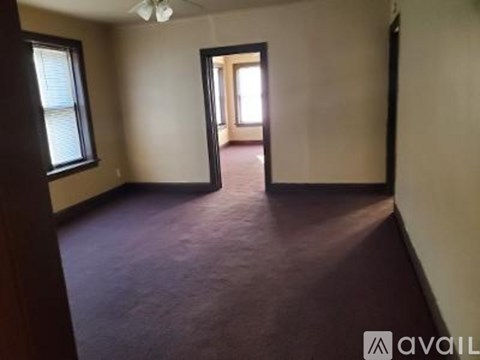 A room with a brown carpet and a doorway leading to another room.