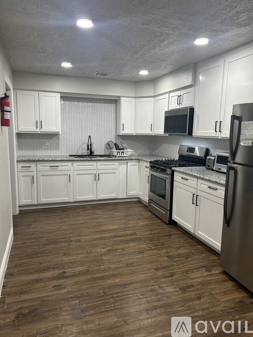 A kitchen with white cabinets and wooden floors.