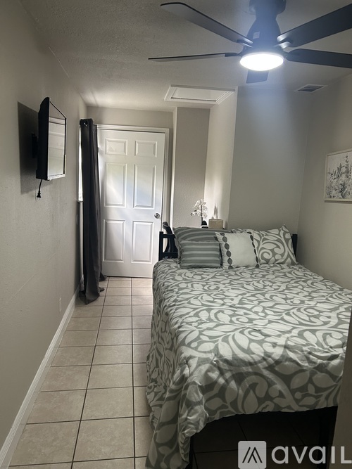A bedroom with a bed, a ceiling fan, and a door.