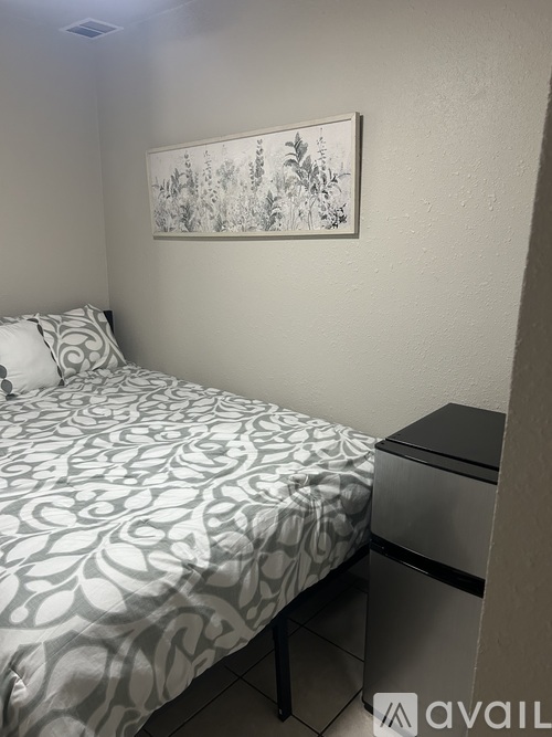 A bedroom with a bed, nightstand, and a framed picture on the wall.
