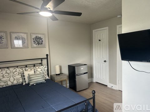 A bedroom with a bed and a ceiling fan is visible through an open door.