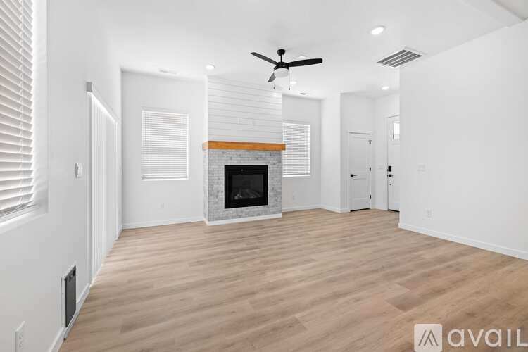 A spacious living room with a fireplace and a ceiling fan.