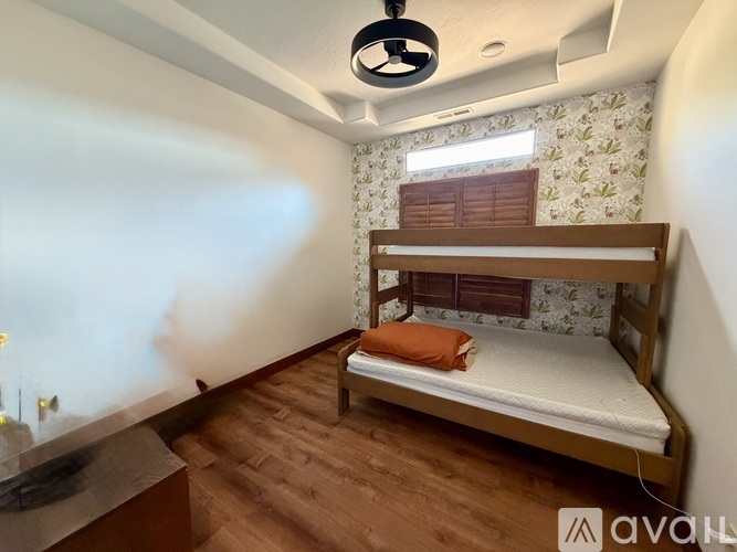A small bedroom with a bunk bed and a window with wooden blinds.