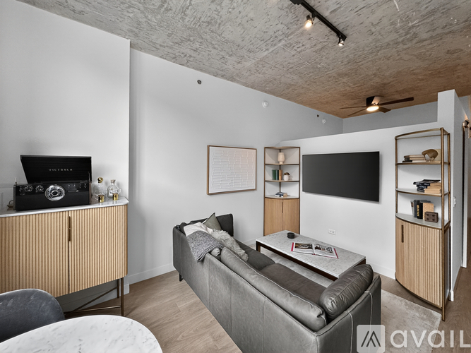 A living room with a grey couch and a television on the wall.