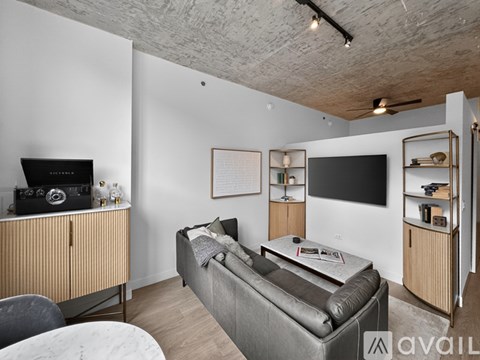 A living room with a grey couch and a television on the wall.