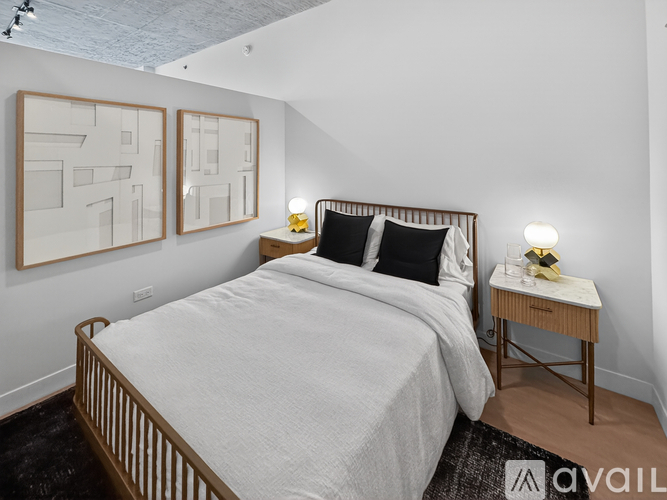 A bedroom with a bed, nightstand, and two framed pictures on the wall.