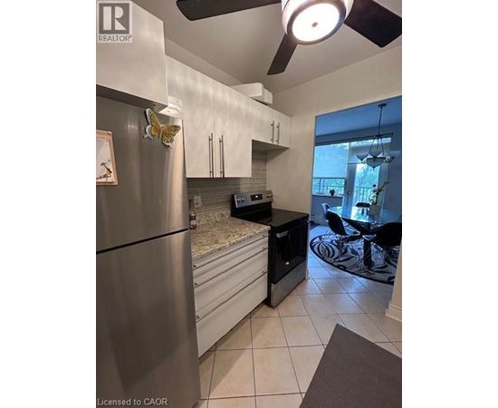 A modern kitchen with a stainless steel refrigerator and black countertops.
