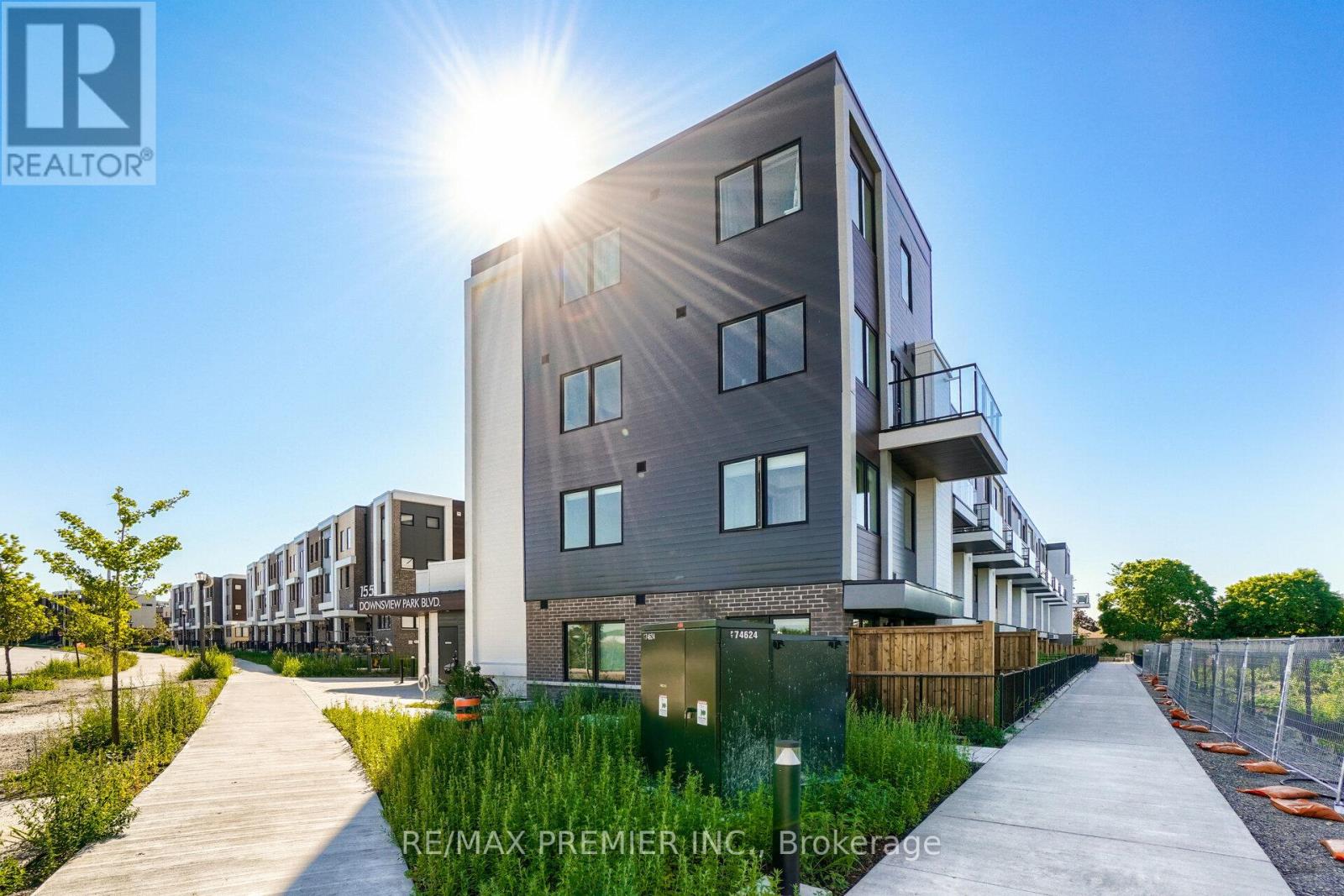 A modern apartment building with a clear blue sky and sun shining in the background.