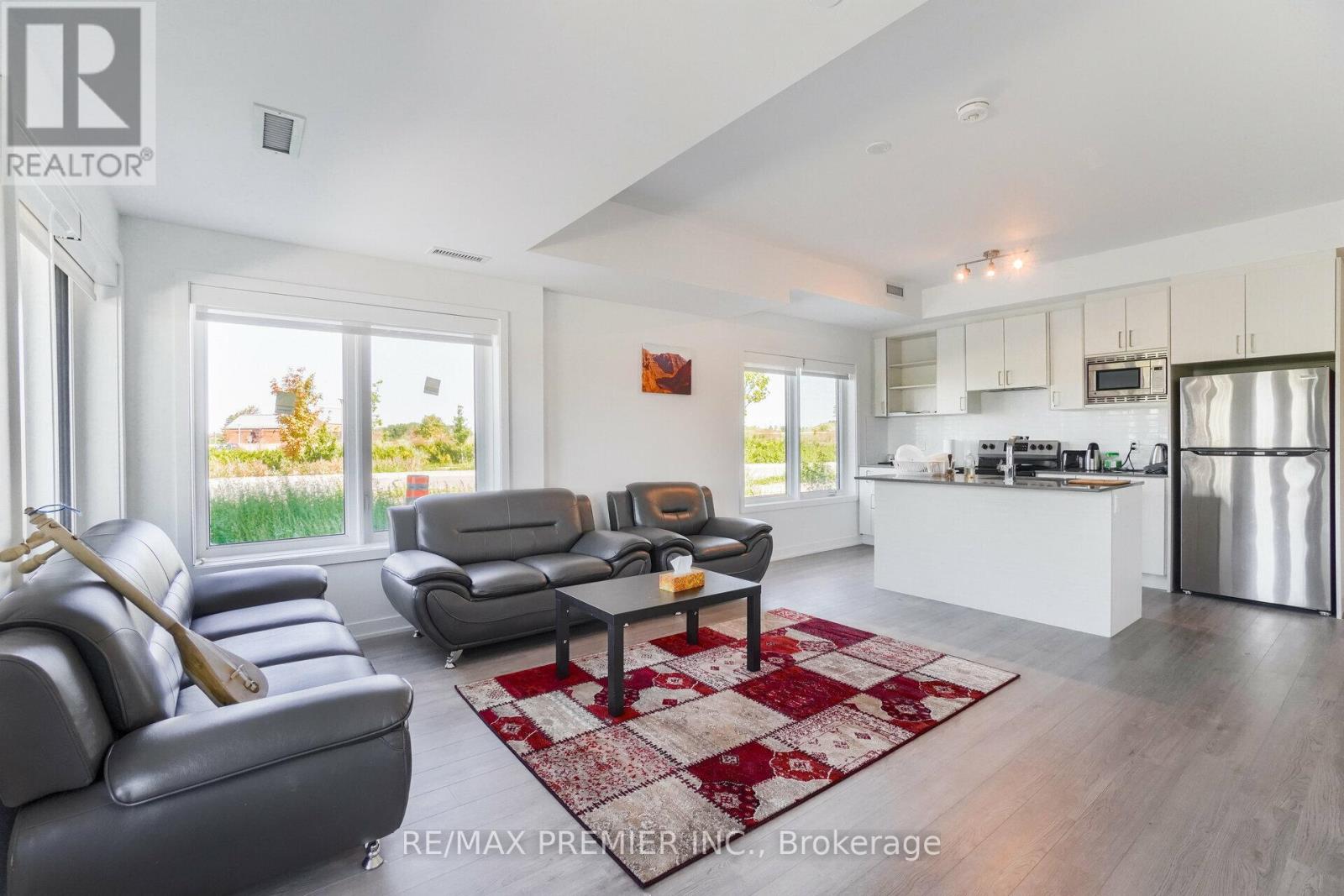 A living room with a grey couch and a red and white rug.