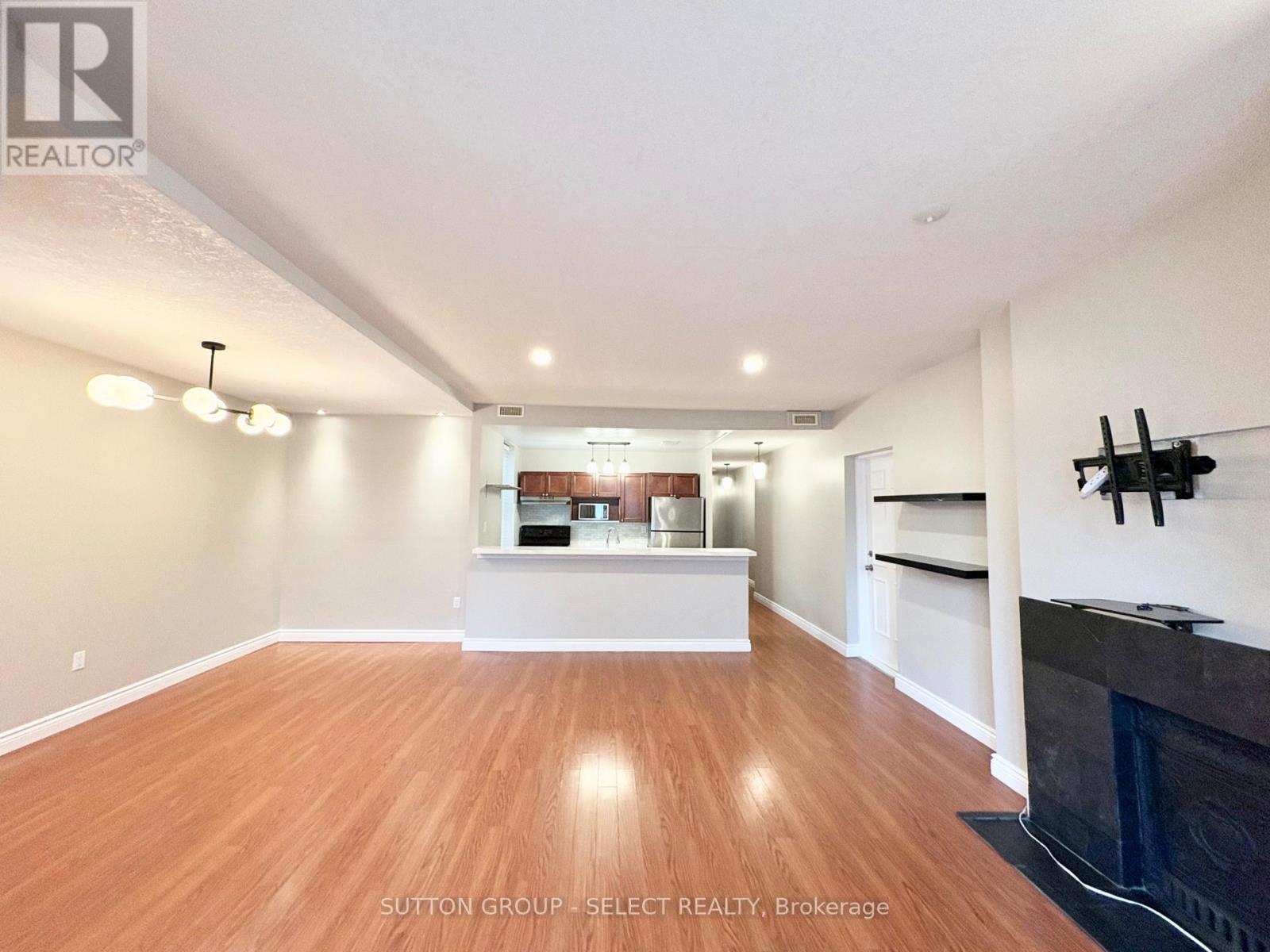 A spacious living room with wood flooring and a fireplace.