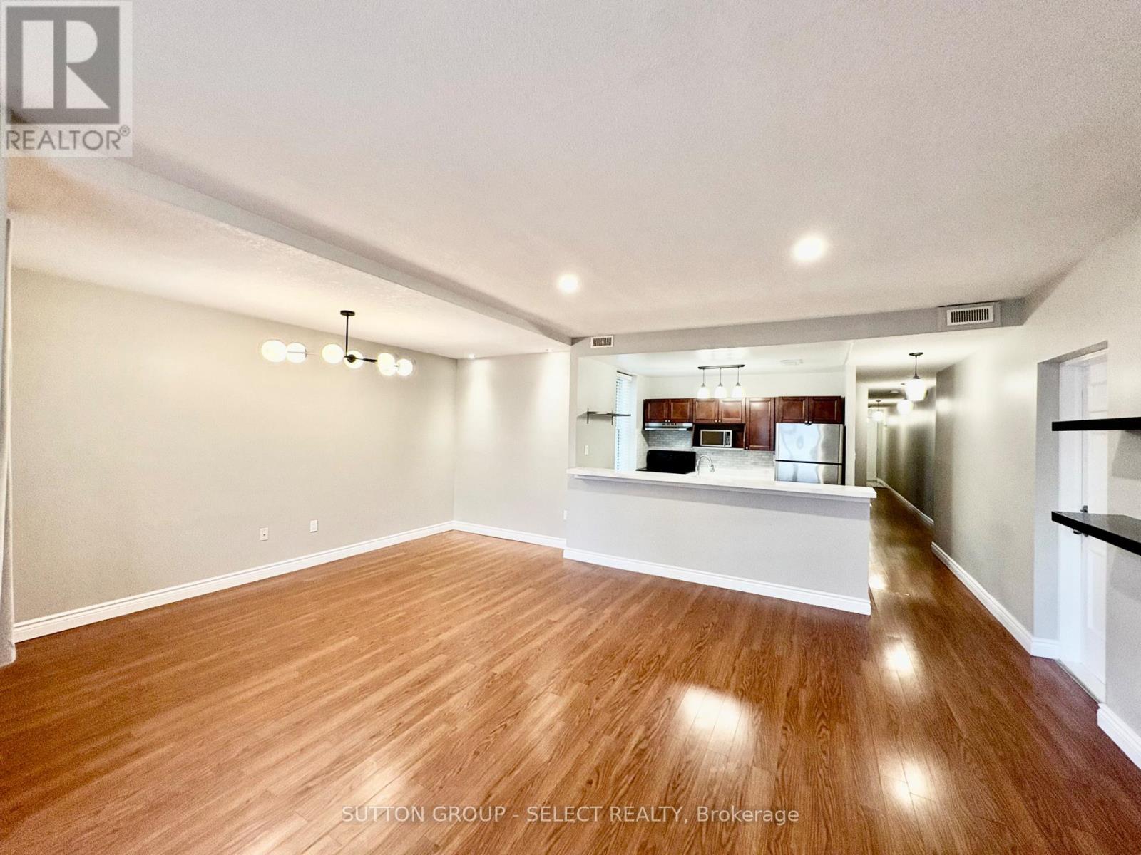 A spacious room with wooden flooring and white walls.