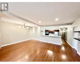 A spacious room with wooden flooring and white walls.