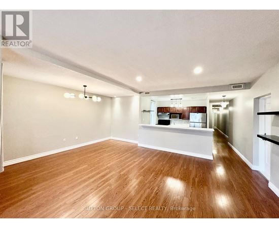 A spacious room with wooden flooring and white walls.