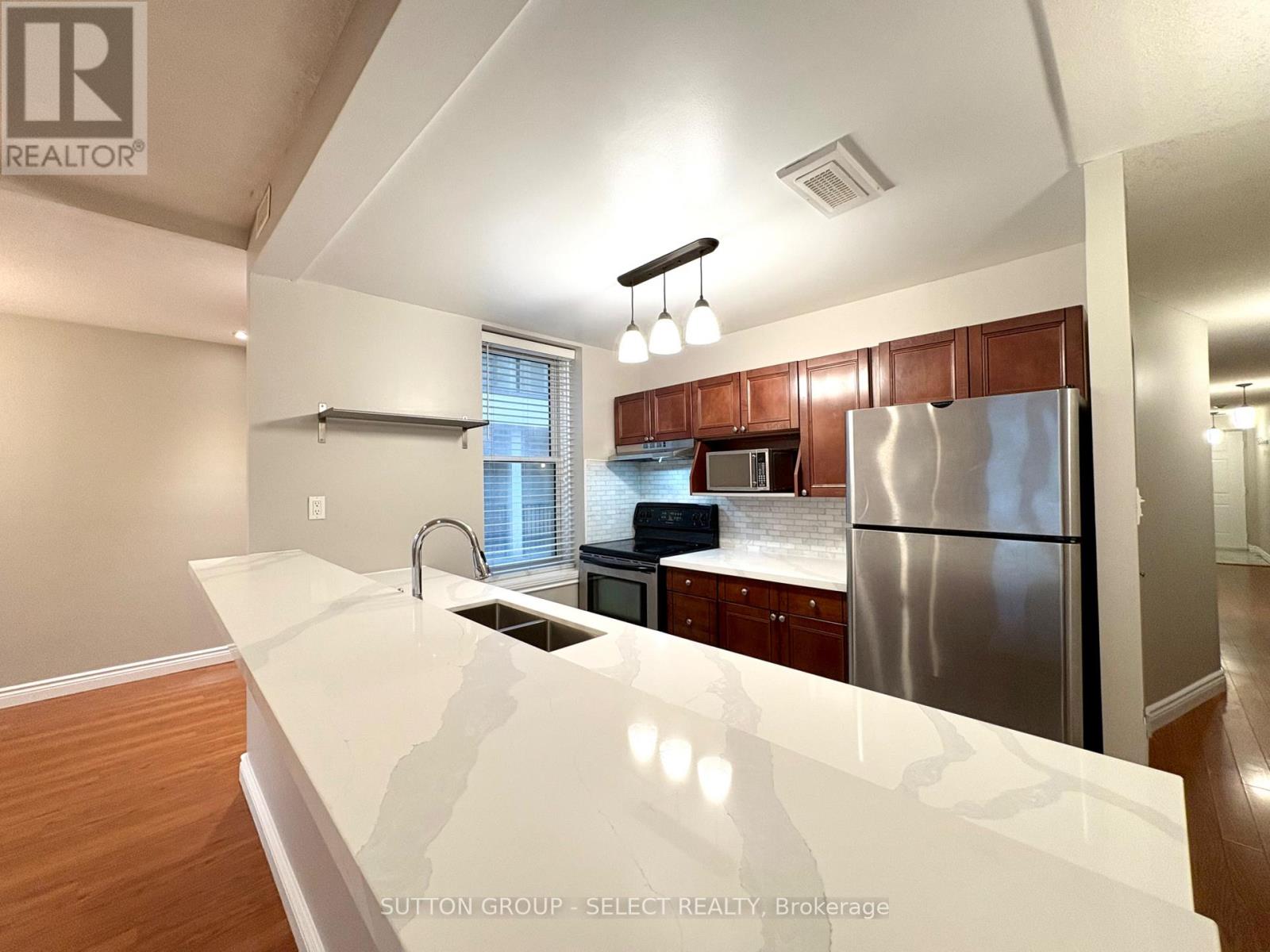 A kitchen with a white counter top and a stainless steel refrigerator.