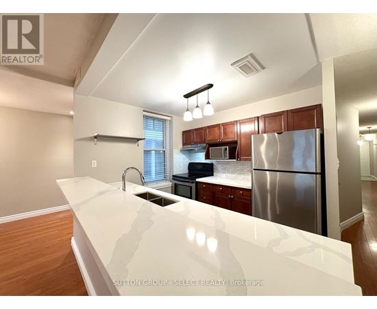 A kitchen with a white counter top and a stainless steel refrigerator.