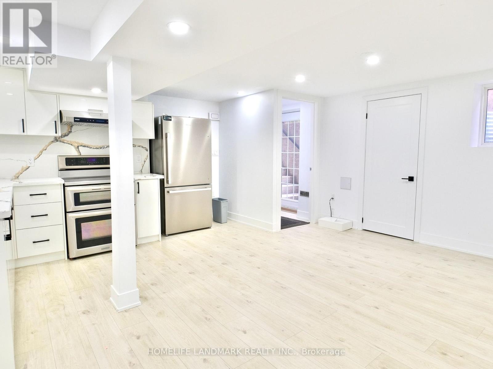 A spacious kitchen with white cabinets and a stainless steel refrigerator.
