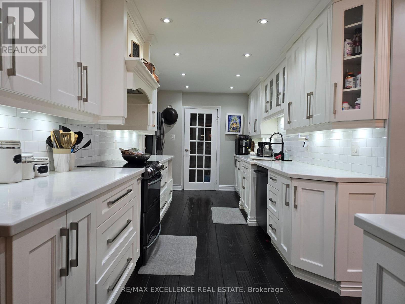 A modern kitchen with white cabinets and a black stove top.