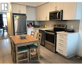 A kitchen with a wooden table and chairs, a refrigerator, a microwave, and a stove top oven.