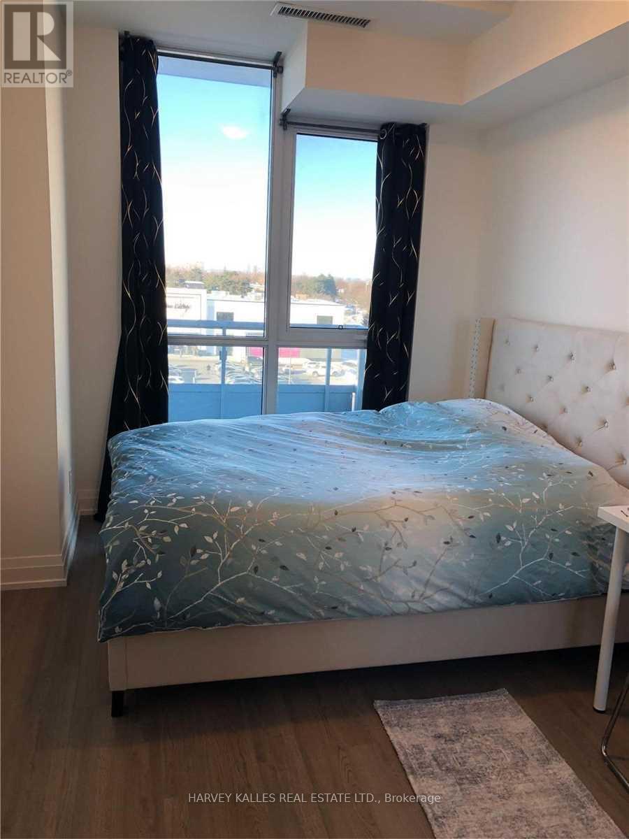 A bedroom with a bed, a window with a view, and a rug on the floor.